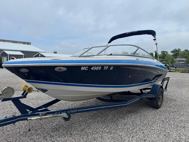 Slide: The Image of 2008 Four Winns H200 boat on trailer, blue and white, parked on gravel. - 7