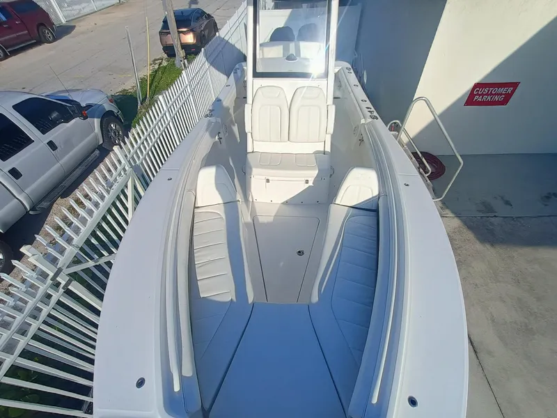 Slide: The Image of 2025 Regulator 23 boat with white interior, parked near a customer parking sign. - 14