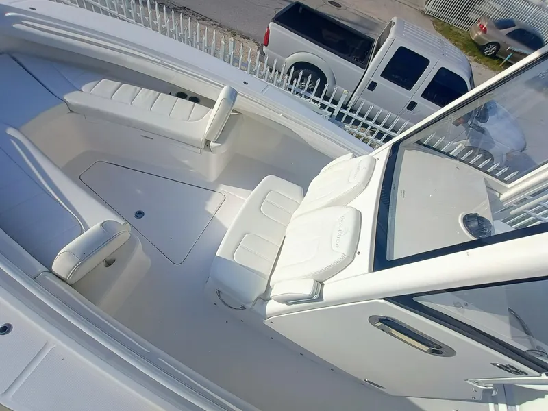 Slide: The Image of 2025 Regulator 23 boat interior with white seating and console, parked near vehicles. - 17