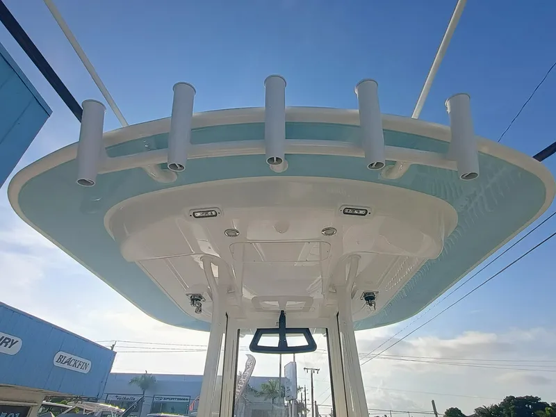 Slide: The Image of 2025 Regulator 23 boat T-top with rod holders against a clear blue sky. - 8