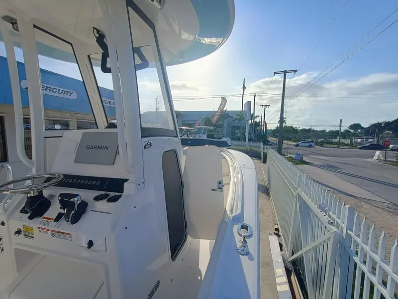 Slide: The Image of 2025 Regulator 23 boat with Garmin navigation, parked near a dealership on a sunny day. - 9