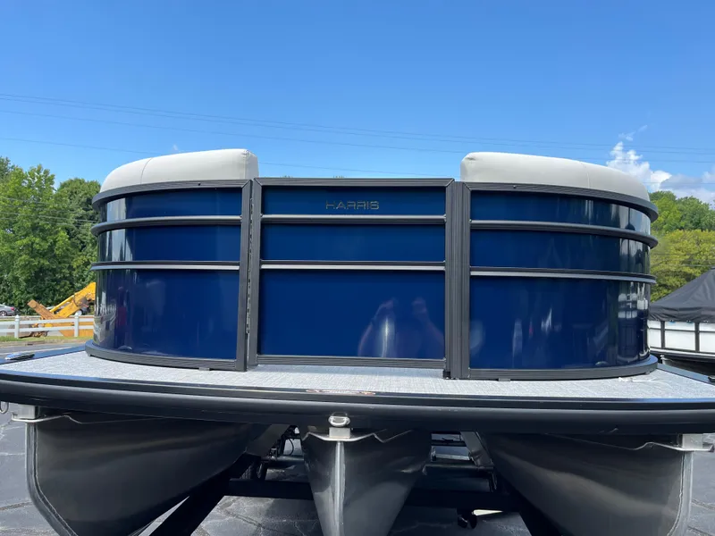 Slide: The Image of 2026 Harris Cruiser 210 pontoon boat with sleek blue exterior under clear sky. - 2