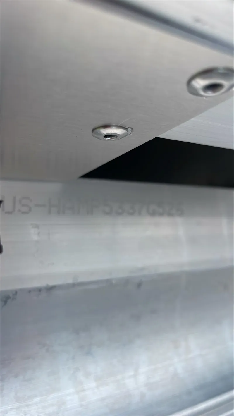 Slide: The Image of Close-up of 2026 Harris Cruiser 210 boat hull with visible rivets and serial number. - 20