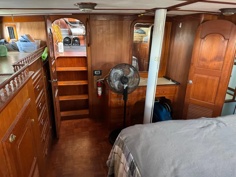 Slide: The Image of 1983 Island Trader Motor Sailor interior with wooden cabinetry, fan, and storage shelves. - 11