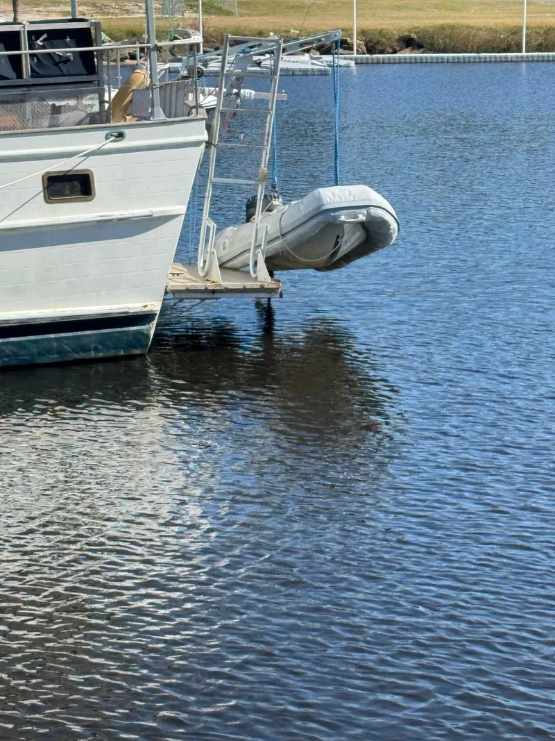 Slide: The Image of 1983 Island Trader Motor Sailor with dinghy on calm water. - 2
