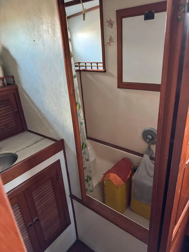 Slide: The Image of 1983 Island Trader Motor Sailor bathroom with wooden cabinets and compact shower area. - 24