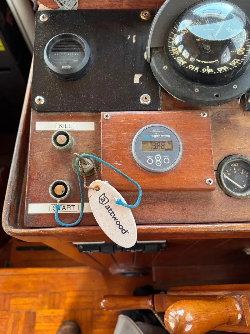 Slide: The Image of Control panel of 1983 Island Trader Motor Sailor with compass, gauges, and keychain. - 26
