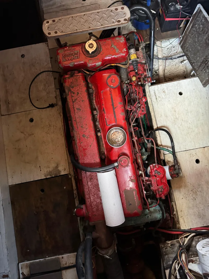 Slide: The Image of 1983 Island Trader Motor Sailor engine, red and weathered, in a wooden compartment. - 31
