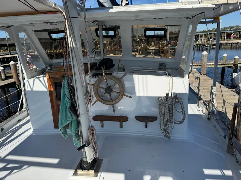 Slide: The Image of 1983 Island Trader Motor Sailor with wooden wheel and ropes, docked at marina. - 7