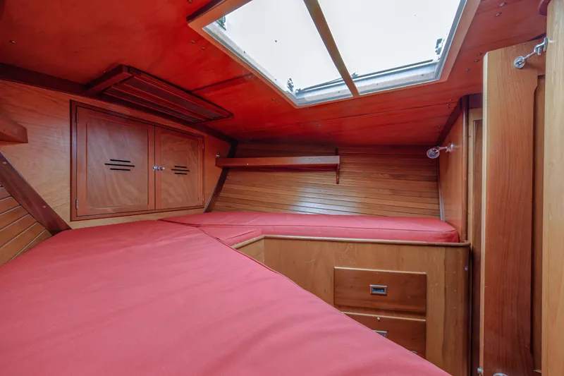 Slide: The Image of Interior cabin of 1972 Hinckley 48 yacht with red cushions and wooden finish. - 46