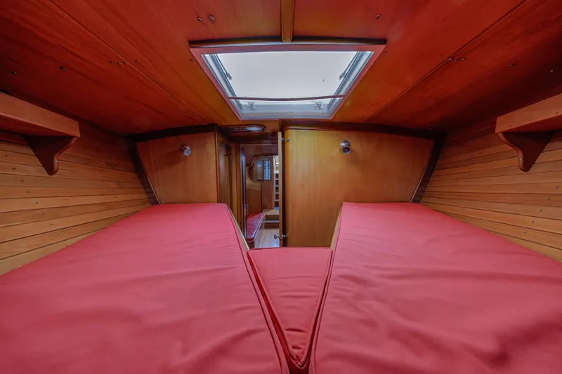 Slide: The Image of Interior cabin of 1972 Hinckley 48 yacht with red bedding and wooden paneling. - 47