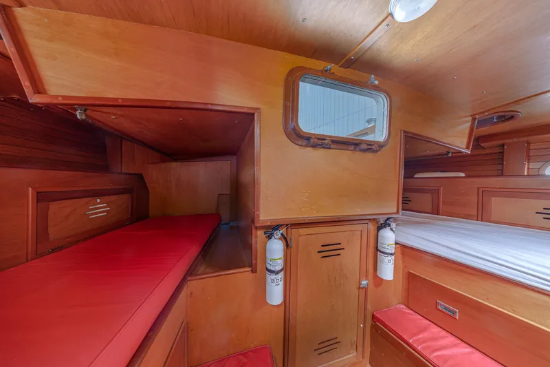 Slide: The Image of Interior of 1972 Hinckley 48 yacht with wooden finish and red cushions. - 48