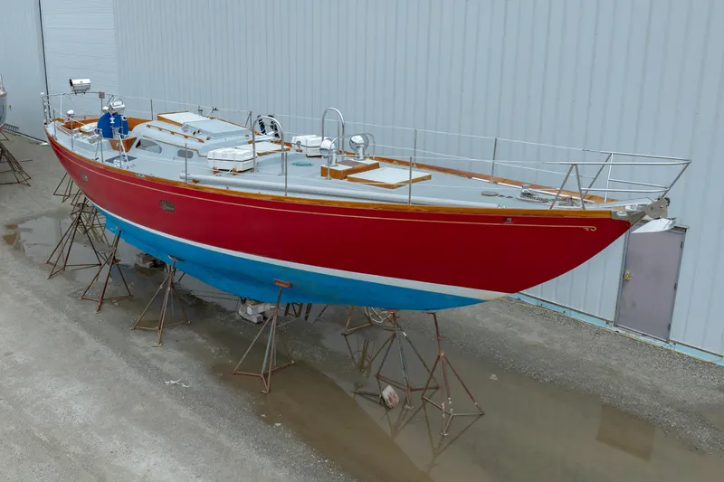 Slide: The Image of 1972 Hinckley 48 sailboat with red hull and blue bottom, displayed on stands. - 6