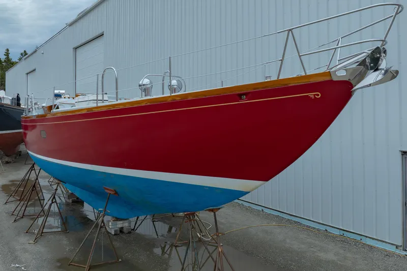 Slide: The Image of 1972 Hinckley 48 sailboat with red hull and blue bottom, docked outside a warehouse. - 9