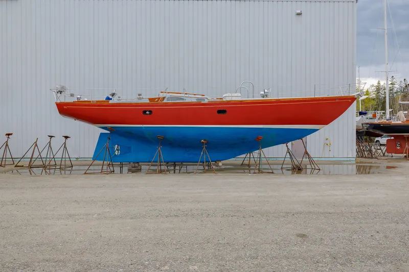 Slide: The Image of 1972 Hinckley 48 sailboat with red hull and blue bottom on stands. - 2