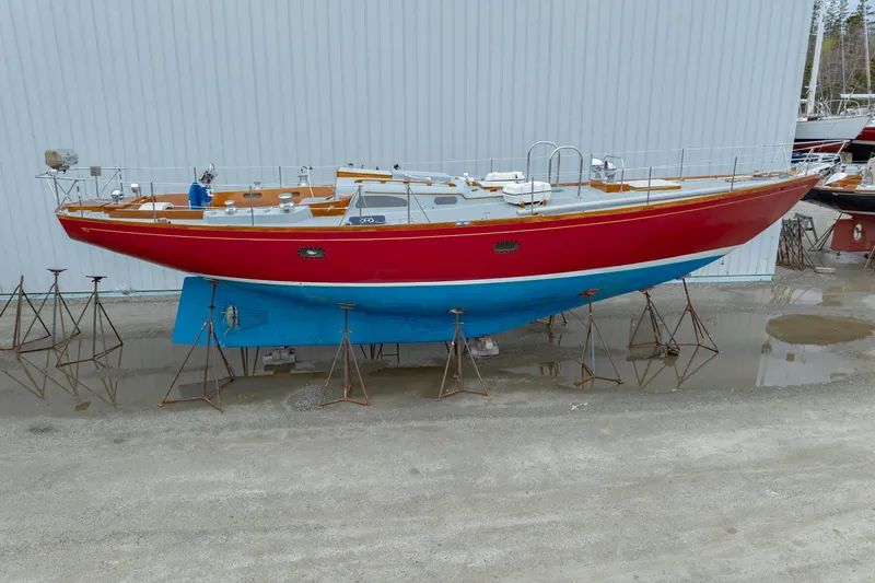 Slide: The Image of 1972 Hinckley 48 sailboat with red hull and blue bottom on stands. - 57