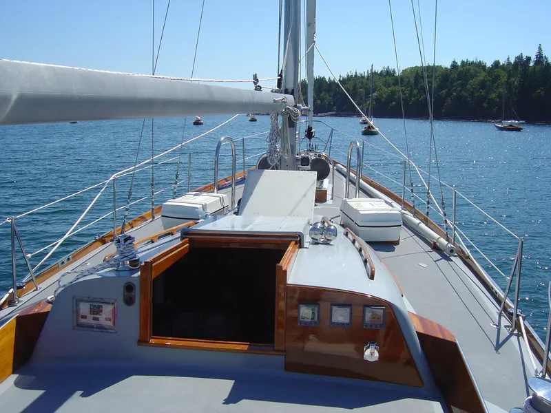 Slide: The Image of Hinckley 48 sailboat deck view, 1972 model, sailing on calm waters with forested shoreline. - 24