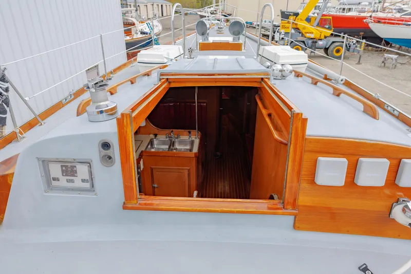 Slide: The Image of Hinckley 48 sailboat interior view, showcasing wooden cabinetry and dual sinks, docked in a marina. - 27