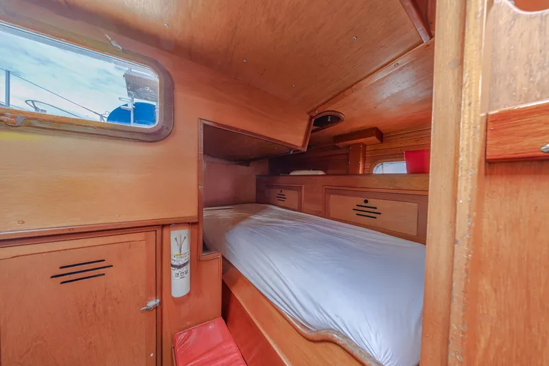 Slide: The Image of Cozy cabin interior of 1972 Hinckley 48 sailboat with wooden furnishings and a single bed. - 49