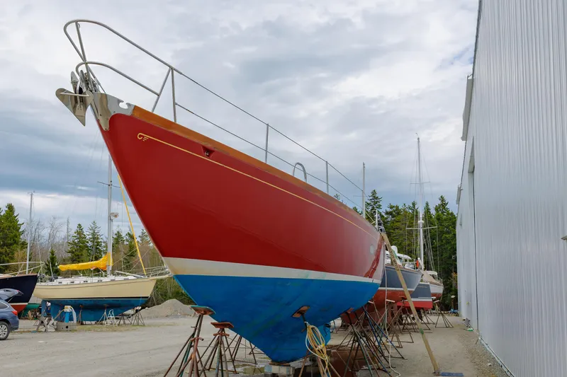Slide: The Image of Red 1972 Hinckley 48 sailboat on dry dock near a white building. - 8