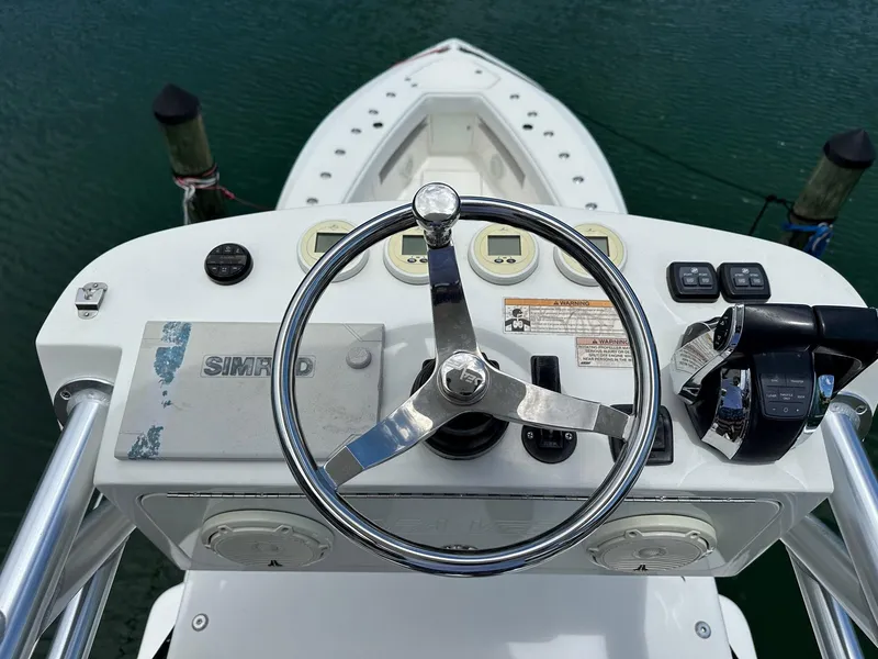 Slide: The Image of 2018 SeaVee 390Z boat helm with steering wheel and controls, docked on calm water. - 15