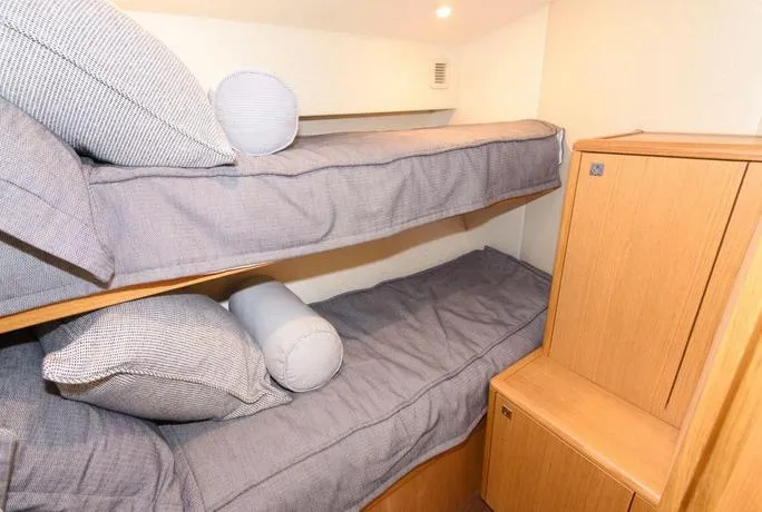 Slide: The Image of Bunk beds in 2015 Hatteras 45 Express Sportfish cabin with gray bedding and wooden storage. - 11