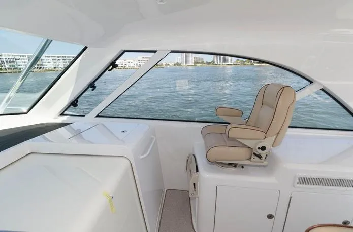 Slide: The Image of 2015 Hatteras 45 Express Sportfish interior with captain's chair and waterfront view. - 13