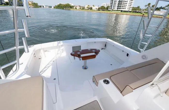 Slide: The Image of 2015 Hatteras 45 Express Sportfish boat deck with seating and table, overlooking calm waters. - 22
