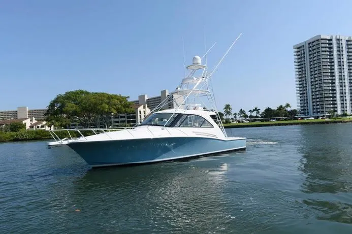 Slide: The Image of 2015 Hatteras 45 Express Sportfish yacht on calm water near urban skyline. - 3