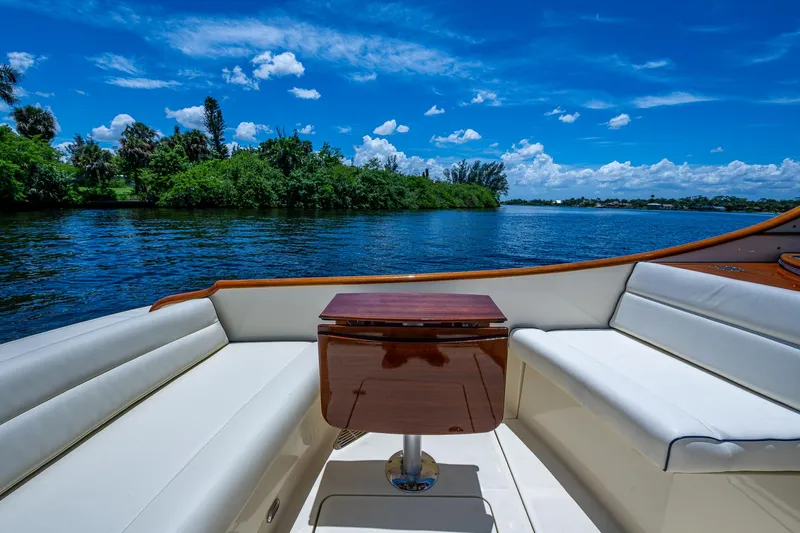 Slide: The Image of 2016 Hinckley Talaria 34 boat interior with white seating and wooden table, scenic water view. - 15