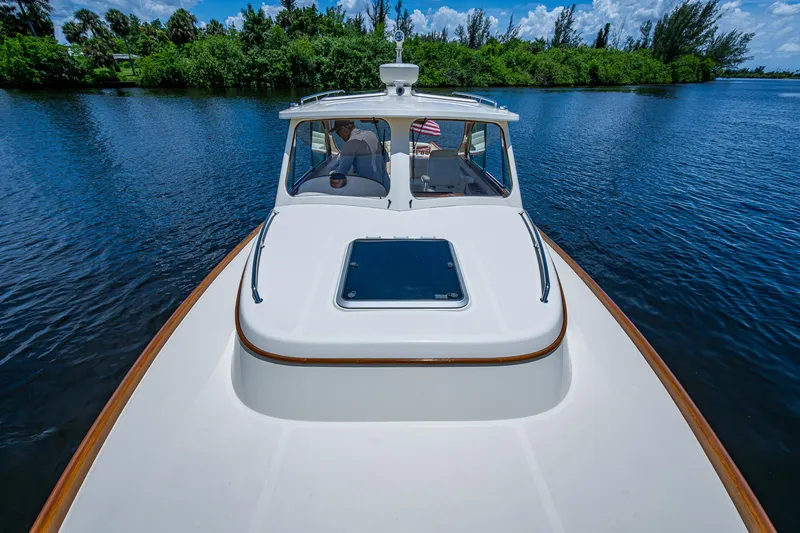 Slide: The Image of 2016 Hinckley Talaria 34 cruising on a serene lake with lush greenery. - 18