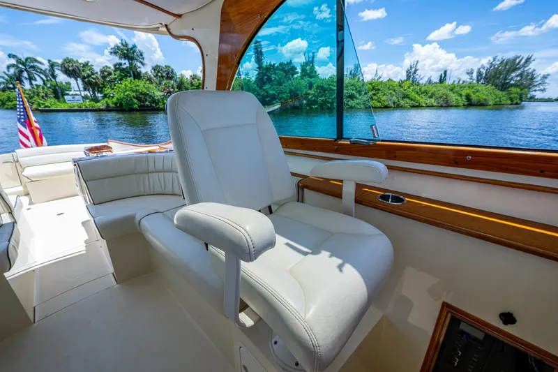 Slide: The Image of 2016 Hinckley Talaria 34 yacht interior with white seating, overlooking a scenic river view. - 7