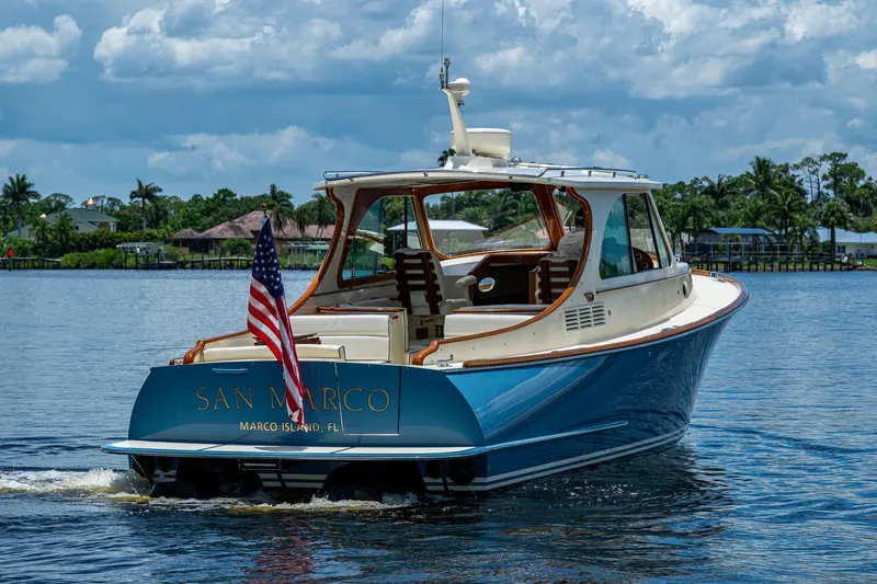 The Image of 2016 Hinckley Talaria 34 yacht cruising on water, American flag displayed, lush background. - 0