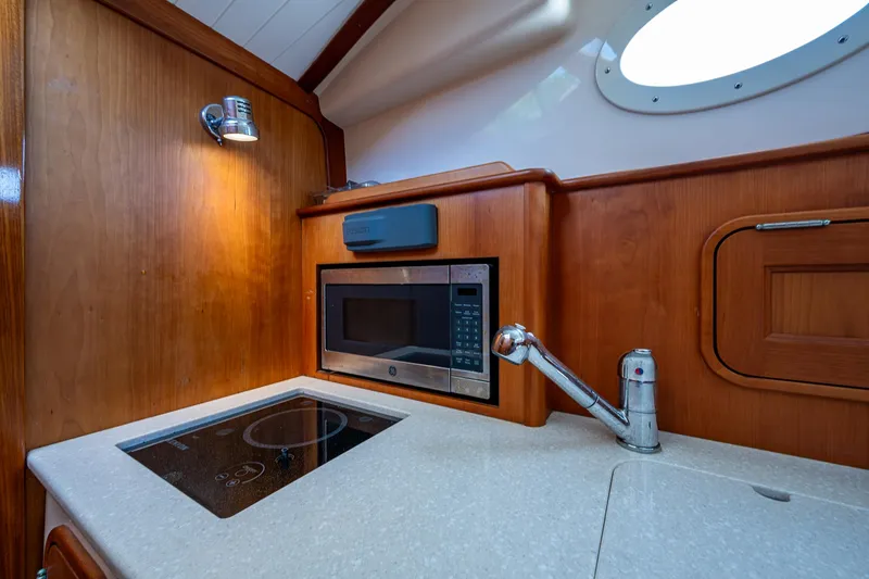 Slide: The Image of Hinckley Talaria 34 yacht kitchen with microwave, induction cooktop, and sink, 2016 model. - 10