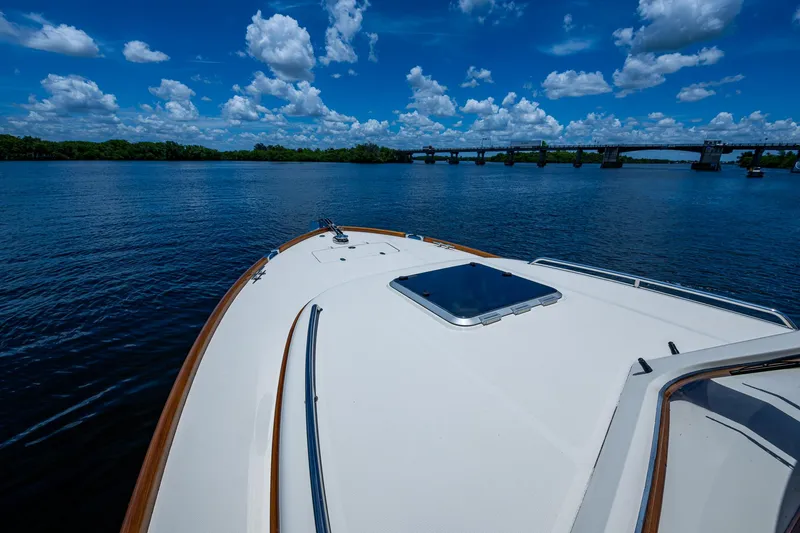 Slide: The Image of Hinckley Talaria 34 yacht on a serene lake with a bridge in the background. - 19