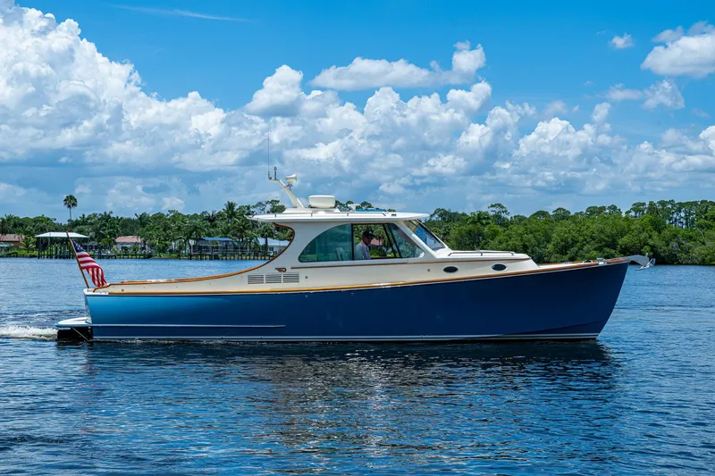 Slide: The Image of 2016 Hinckley Talaria 34 cruising on a sunny day with lush greenery in the background. - 20