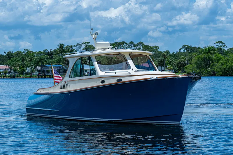 Slide: The Image of 2016 Hinckley Talaria 34 yacht on a serene lake with lush greenery. - 21