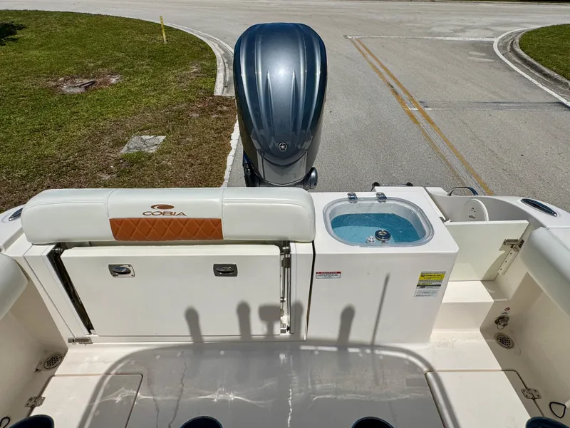 Slide: The Image of 2022 Cobia 237 Center Console boat with outboard motor and livewell, parked on a road. - 20
