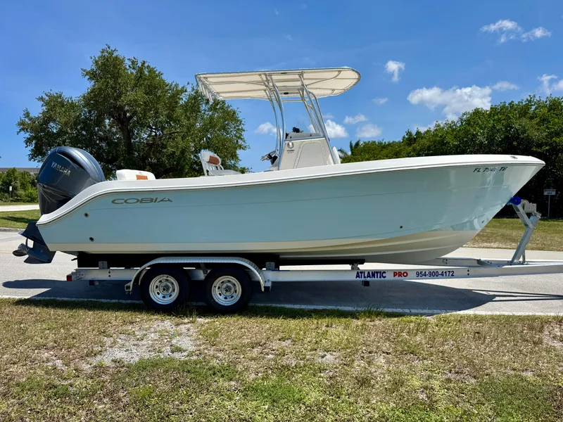 Slide: The Image of 2022 Cobia 237 Center Console boat on trailer, parked outdoors under clear sky. - 5