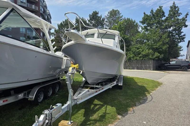 Slide: The Image of 2025 Parker 2820 XLD boat on trailer, parked outdoors near trees and buildings. - 6