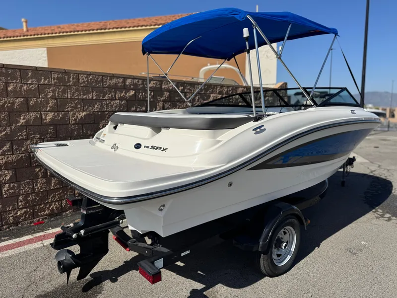 Slide: The Image of 2015 Sea Ray 19 SPX boat with blue canopy on trailer, parked outdoors. - 5