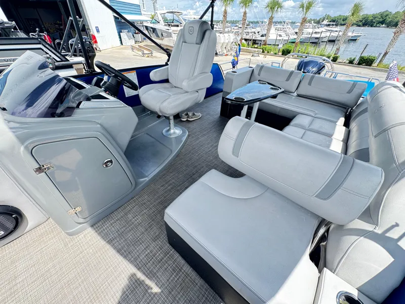 Slide: The Image of 2019 AquaPatio 259 DFL pontoon boat interior with gray seating and helm, dockside view. - 12