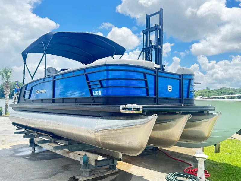 Slide: The Image of 2019 AquaPatio 259 DFL pontoon boat with blue exterior, docked under a sunny sky. - 14