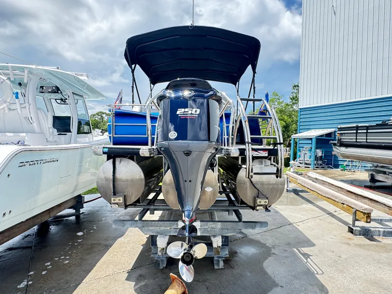 Slide: The Image of 2019 AquaPatio 259 DFL pontoon boat on trailer, with blue accents and black canopy. - 15