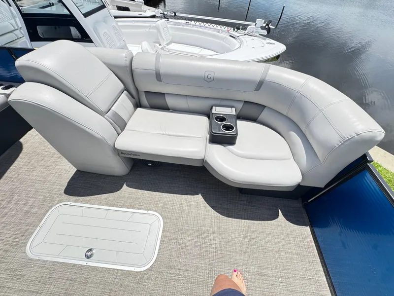 Slide: The Image of 2019 AquaPatio 259 DFL boat with luxurious white seating and cup holders by the water. - 8