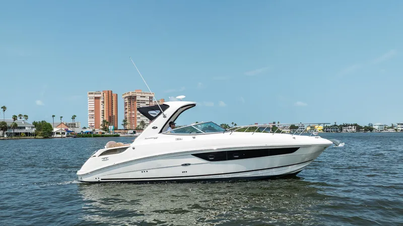 The Image of 2016 Sea Ray 310 Sundancer cruising on a sunny day near waterfront buildings. - 0