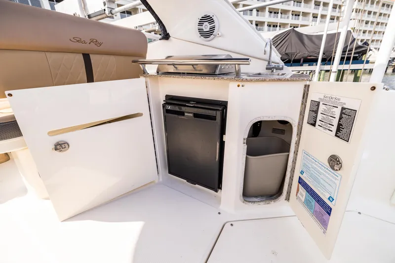 Slide: The Image of 2016 Sea Ray 310 Sundancer boat interior with kitchenette and storage compartments. - 31