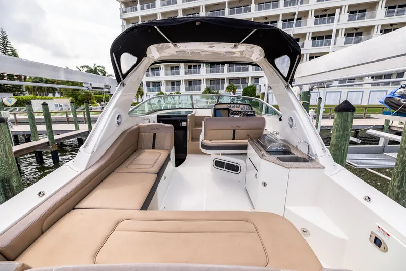 Slide: The Image of 2016 Sea Ray 310 Sundancer boat interior with seating and kitchenette at a marina. - 35