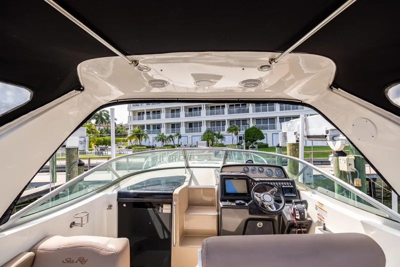 Slide: The Image of 2016 Sea Ray 310 Sundancer cockpit with modern controls, docked near waterfront buildings. - 36