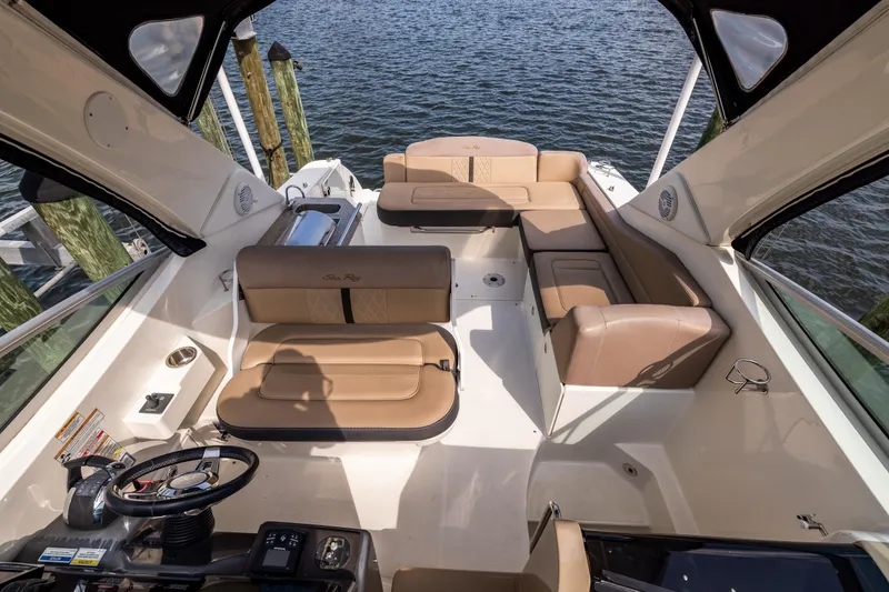 Slide: The Image of 2016 Sea Ray 310 Sundancer boat interior with tan seating and steering wheel, docked by water. - 37